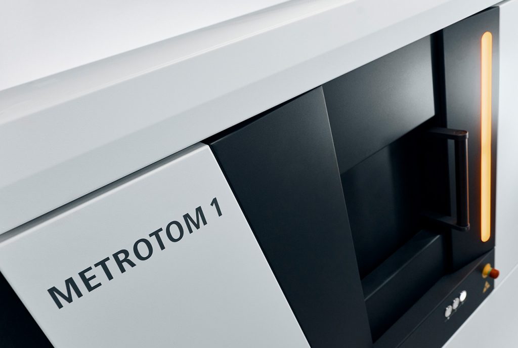 Angled view on a black and white CT scanner with an orange light turned on on the front