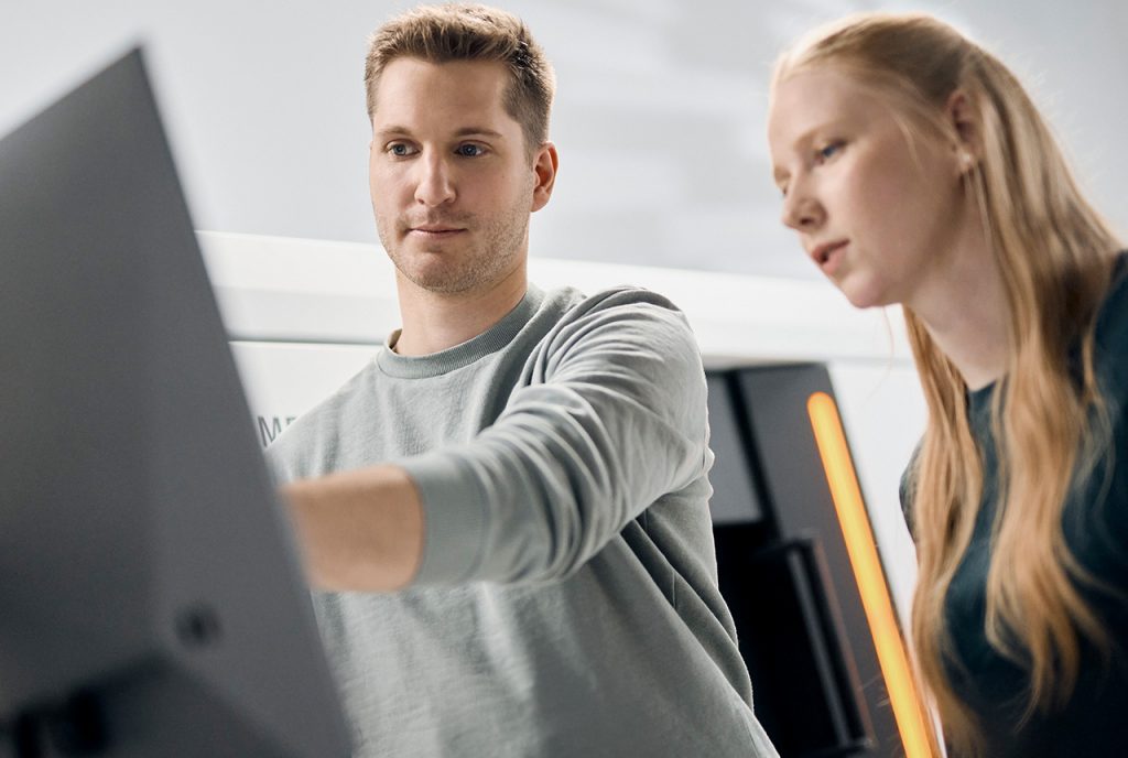 A man and a woman looking at a screen, standig infront of a CT scanner