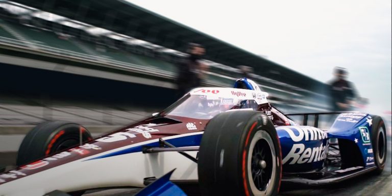 A blue, red and white racing car in front of a blured background
